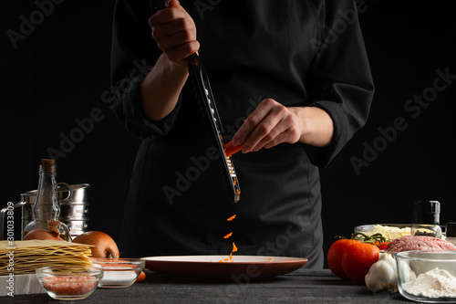 chef rubs carrots, freeze in motion for cooking Italian lasagna. Restaurant and hotel business, recipe book, menu