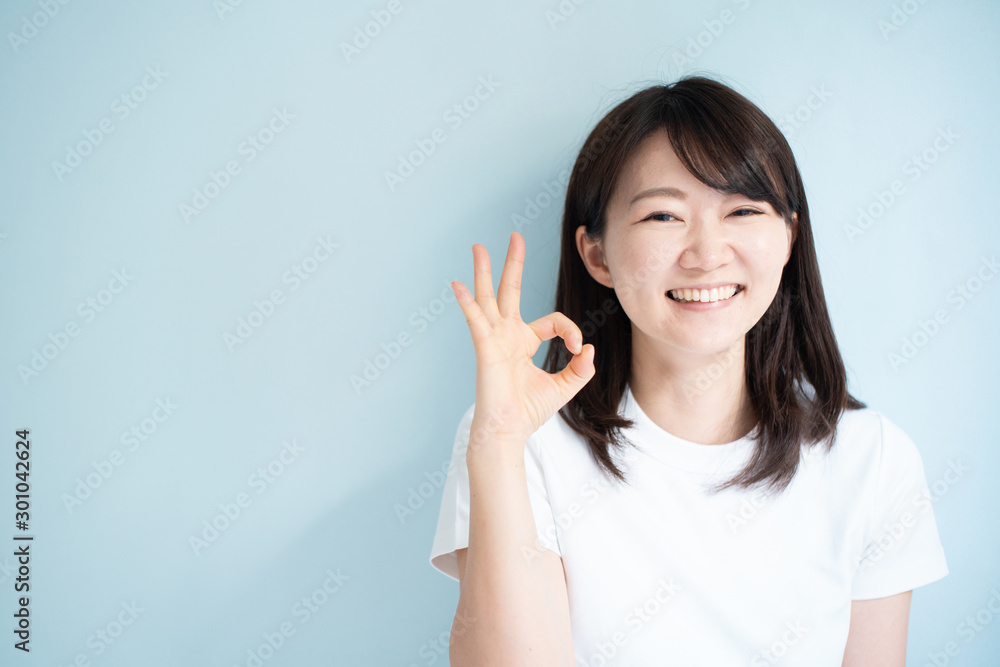 Young woman shoing OK gesture against light blue background Young woman shoing OK gesture against light blue background