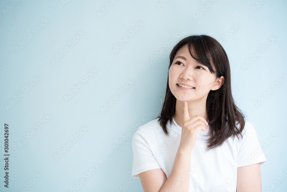 Thinking young woman against light blue background Thinking young woman against light blue background