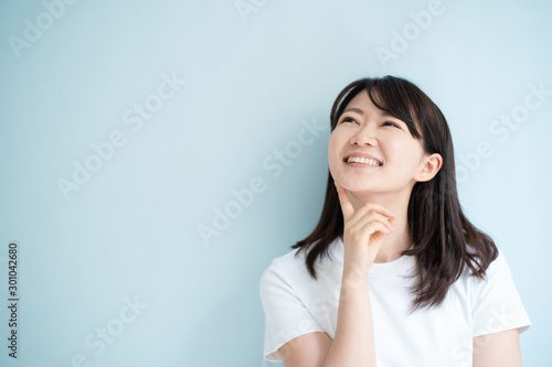 Thinking young woman against light blue background