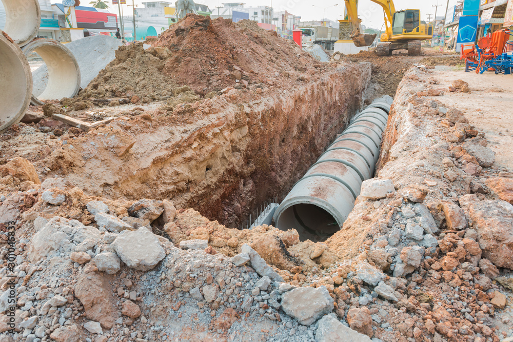 Concrete drainage tube row underground near construction site.Concrete pipe stacked sewage water system aligned on site. Concrete drainage tube row underground near construction site.Concrete pipe stacked sewage water system aligned on site.