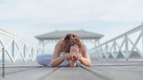 Young women practice yoga on the white bridge by the sea, the concept of enjoying privacy and the concentration of sunlight.