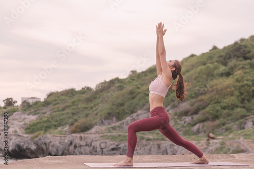 Young women doing yoga, practicing yoga postures on the mountain range Yoga landscape Beautiful sky and enjoying the sea view On the concept of exercise, health care