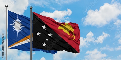 Marshall Islands and Papua New Guinea flag waving in the wind against white cloudy blue sky together. Diplomacy concept, international relations.