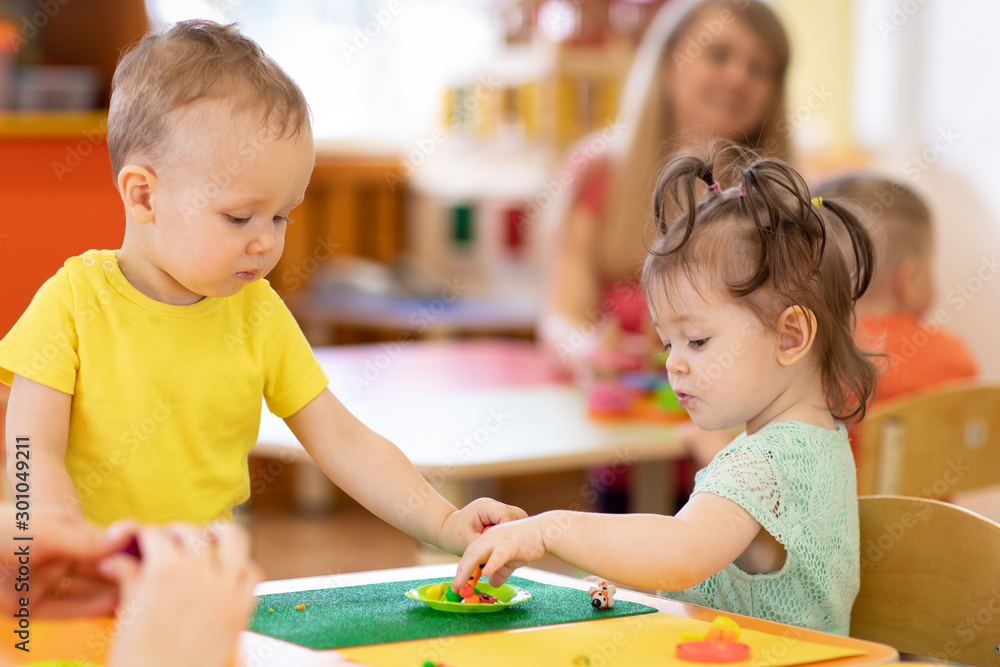 Fototapeta premium Kids group making arts and crafts in kindergarten. Children on lesson in day care centre