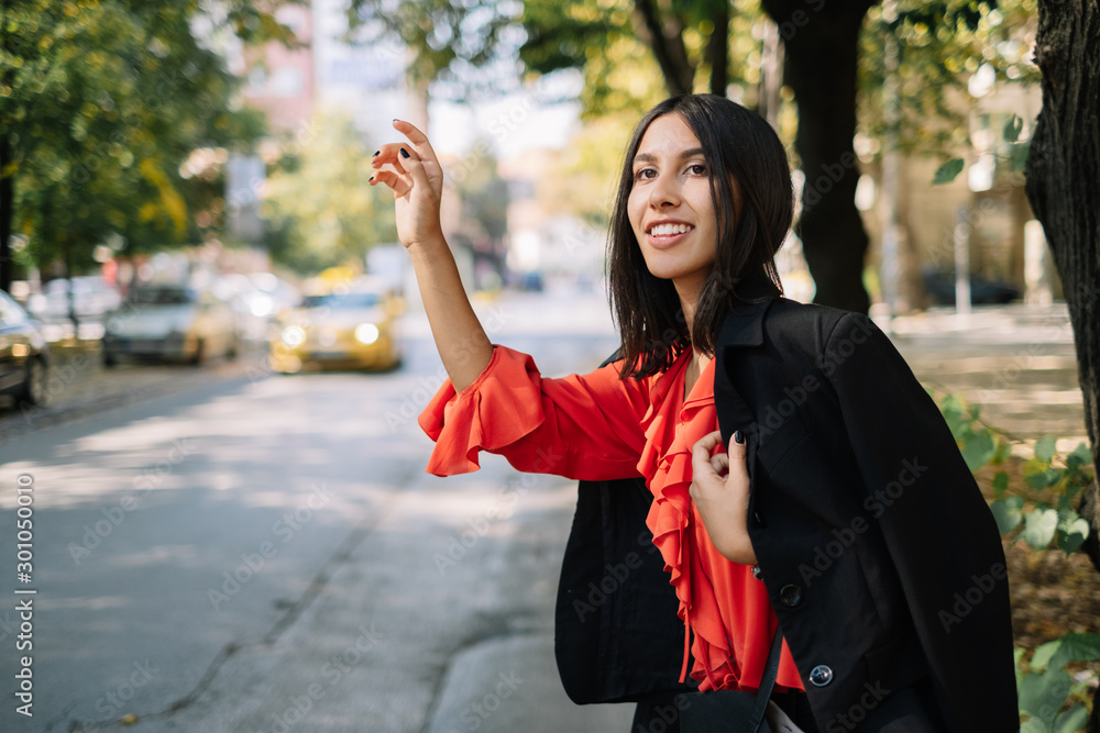 Girl smiling while waving for taxi on street Girl smiling while waving for taxi on street