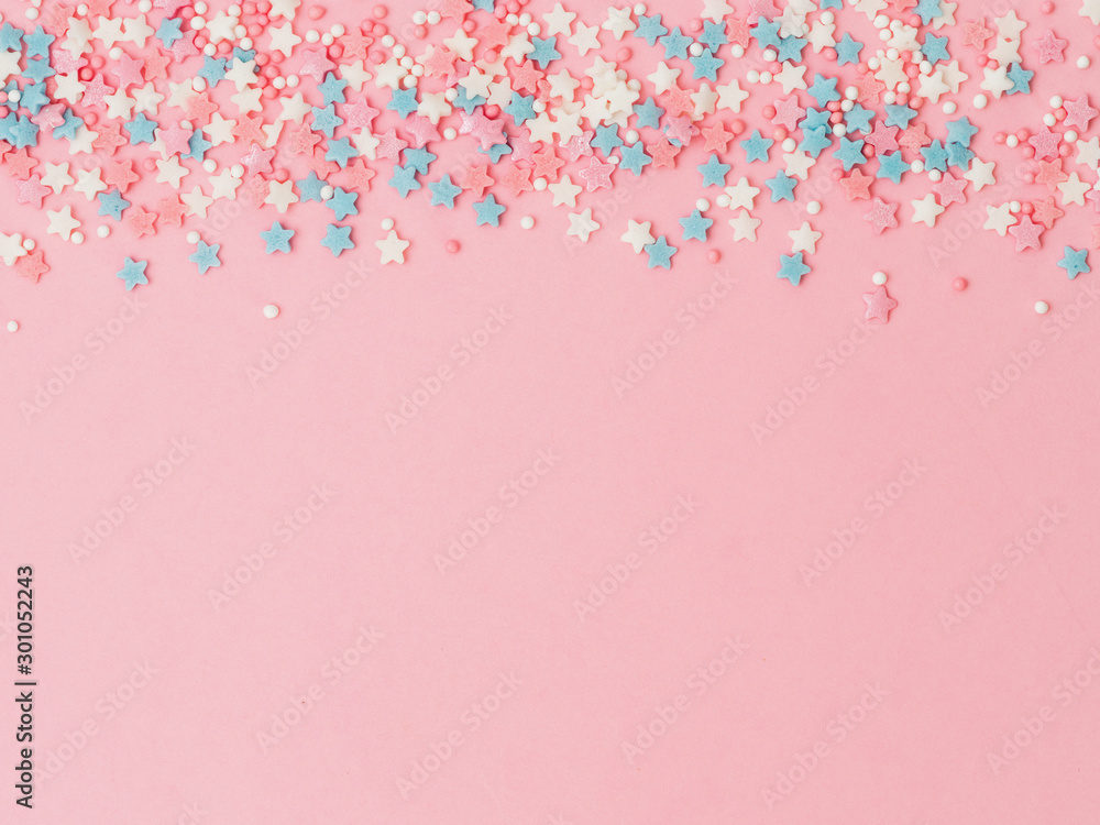 Festive border frame of colorful pastel sprinkles on pink background, copy space top. Sugar sprinkle dots and stars, decoration for cake and bakery. Top view or flat lay - obrazy, fototapety, plakaty 