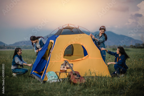 Group A girl friend in casual clothes and enjoys camping in the forest. The young woman helping each other out with a tent to sleep in the forest at night. Camping and travel concept.