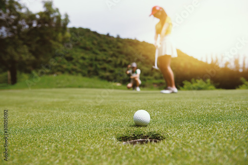 Golfer putting golf ball on the green golf, lens flare on sun set evening time.