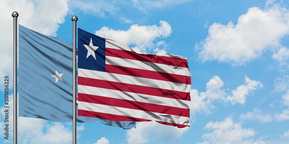 Obraz premium Micronesia and Liberia flag waving in the wind against white cloudy blue sky together. Diplomacy concept, international relations.