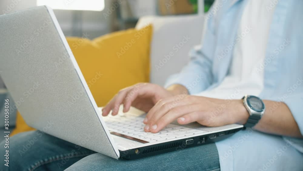 Freelancer seat on sofa in modern living room and typing on laptop keyboard. Close up 4k slow motion footage. Freelancer seat on sofa in modern living room and typing on laptop keyboard. Close up 4k slow motion footage.