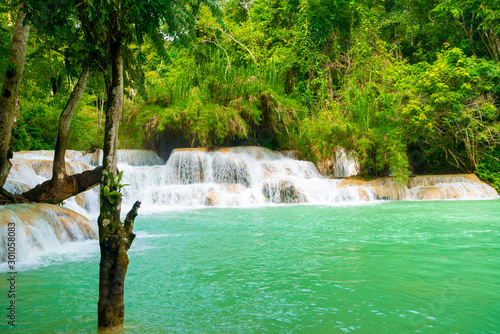 Tat Kuang Si Falls near to popular travel destination Luang Prabang in Laos. Three level waterfall with turquoise blue pools surrounded with lush green tropical jungle.