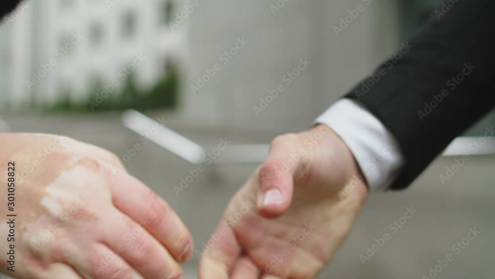 Two businessmen negotiators wear suits shake hands after successful negotiations in the street Two businessmen negotiators wear suits shake hands after successful negotiations in the street