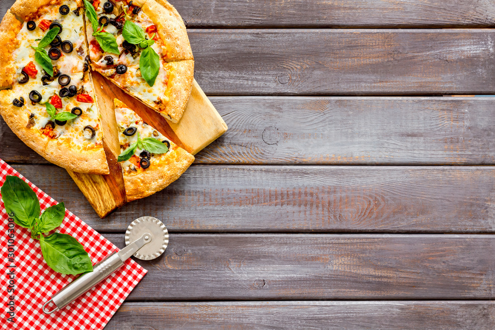 Pizza with tomato, basil, olives, cheese on dark wooden background top view copy space Pizza with tomato, basil, olives, cheese on dark wooden background top view copy space