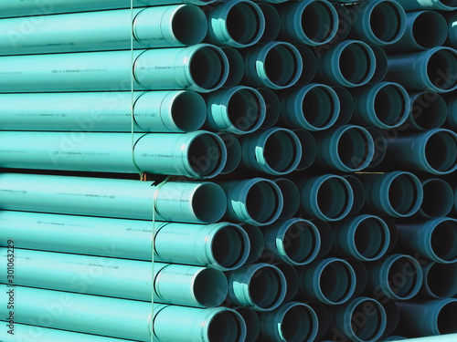 PVC plastic pipes stacked at the construction site ready to be laid as a sewer line. Interesting contrast between highlights and shadows produces patterns of straight lines and circular end view.