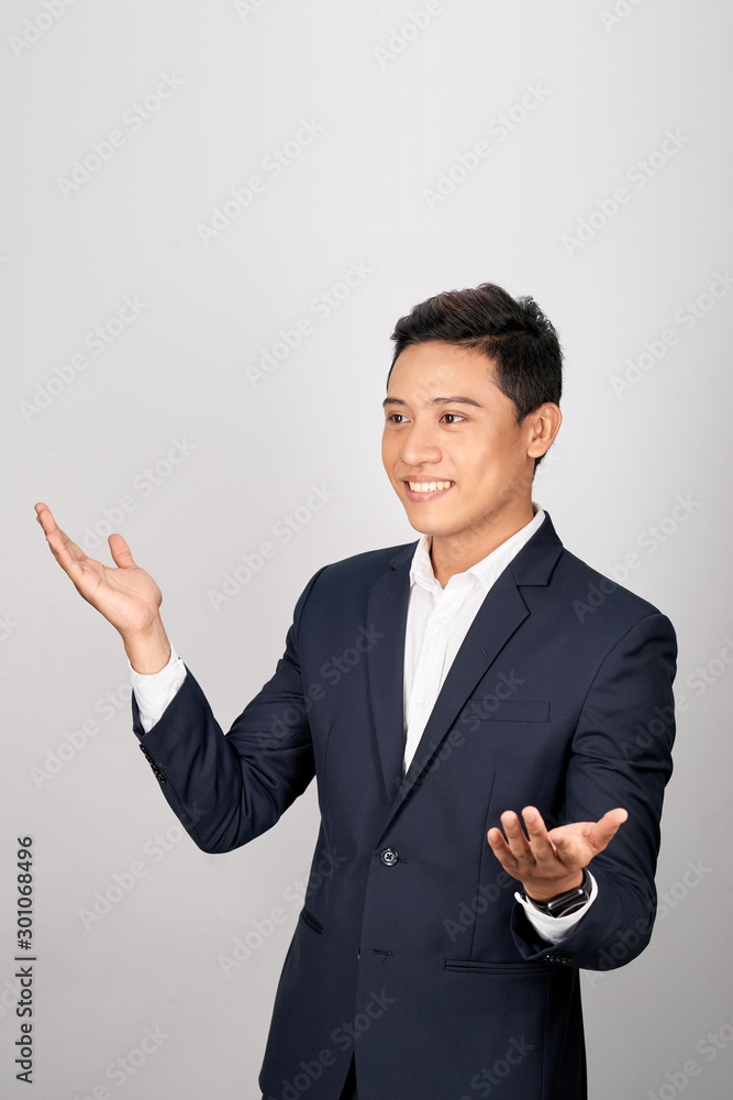 Charming handsome young Asian business man holding his hand up to show present sell product. Isolated on white background Charming handsome young Asian business man holding his hand up to show present sell product. Isolated on white background