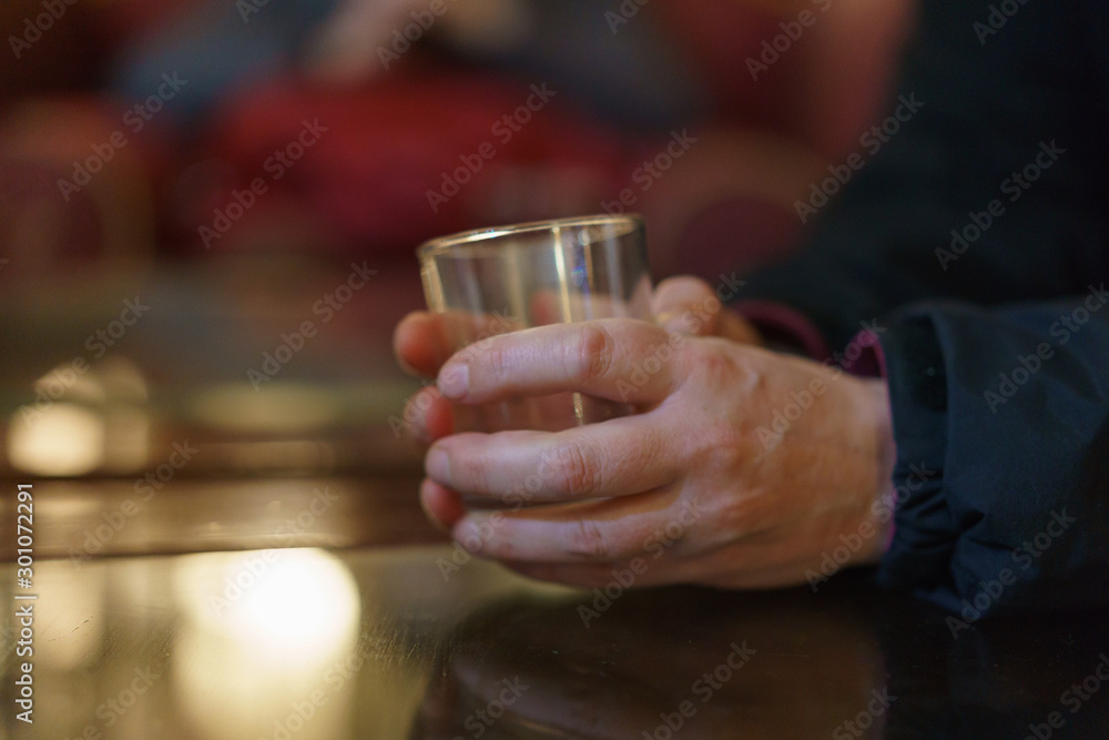 Women hands holding whiskey glass over the table. Photography with defocused background.