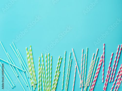 Colorful paper straws on blue background. Ecology product. Equipment for single use. Plastic alternative. Zero waste concept. Copy space for text or design. Top view or flat lay
