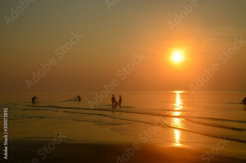  Tropical coastal sunrise landscape waterscape with net fishermen in the ocean water. Huay Yang, Thailand.