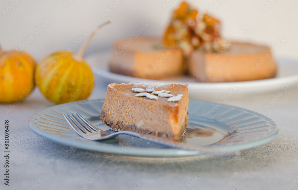 Pumpkin pie or cheesecake with caramel  on decorative plate. Whole pie in soft focus in background. Macro with shallow dof