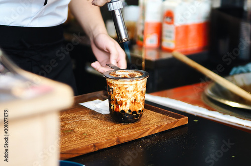 a cup of brown sugar flavored tapioca pearl bubble milk tea in night market of Taiwan background,