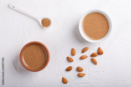 Apricot kernel butter smooth, urbech. Natural paste from apricot kernels in white bowls on white table. Top view. Copy space. photo