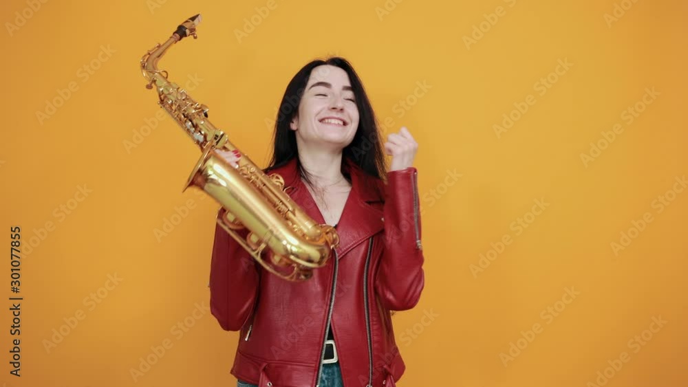 Crazy young woman in casual clothes posing isolated on orange background. People lifestyle concept. Depicting heavy metal rock sign horns up gesture, showing tongue Crazy young woman in casual clothes posing isolated on orange background. People lifestyle concept. Depicting heavy metal rock sign horns up gesture, showing tongue