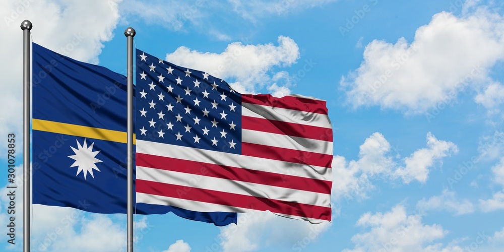 Nauru and United States flag waving in the wind against white cloudy blue sky together. Diplomacy concept, international relations.