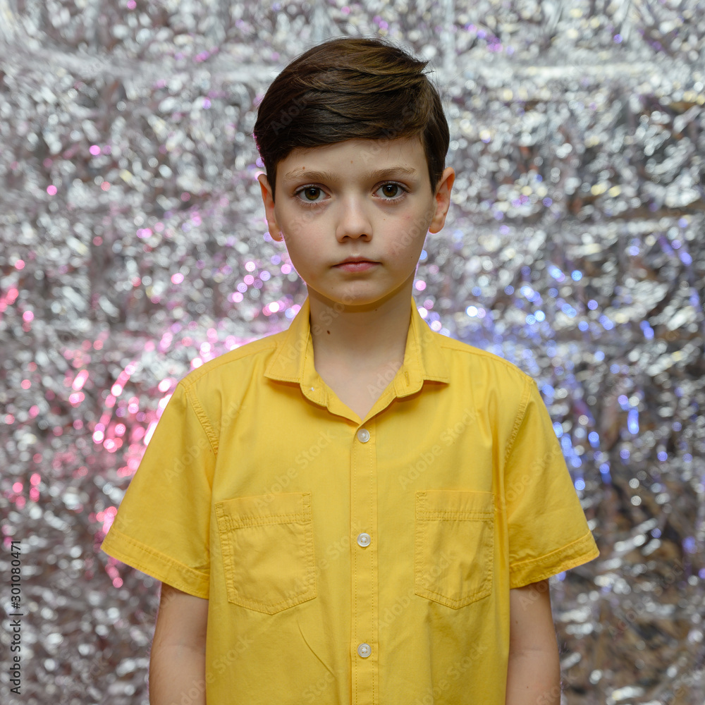 Holiday photo concept for teenager boy. Portrait of a baby boy on a shiny background in a yellow shirt. Stands in front of the camera in different poses with emotions. Holiday photo concept for teenager boy. Portrait of a baby boy on a shiny background in a yellow shirt. Stands in front of the camera in different poses with emotions.
