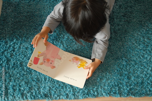 Toddler lying on stomach reading a picture book, top view, open animal book for children　絵本を読む子供