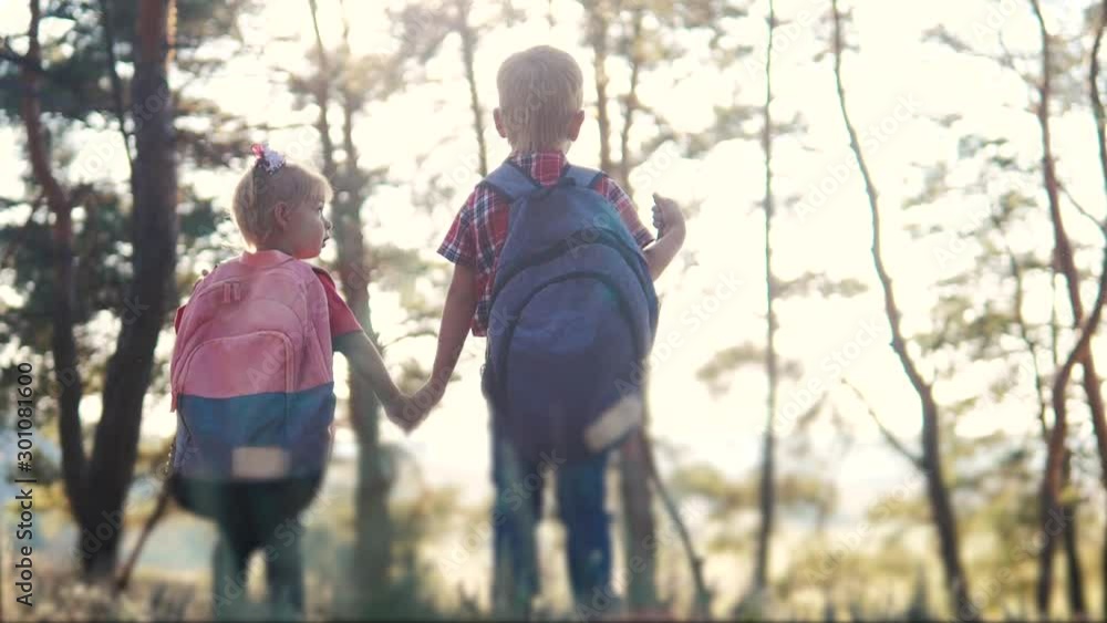 happy family little boy and girl tourists teamwork hold hand scouts tourists slow motion video concept. brother holds sister's hand tourists with backpacks hiking in the forest lifestyle . group of happy family little boy and girl tourists teamwork hold hand scouts tourists slow motion video concept. brother holds sister's hand tourists with backpacks hiking in the forest lifestyle . group of