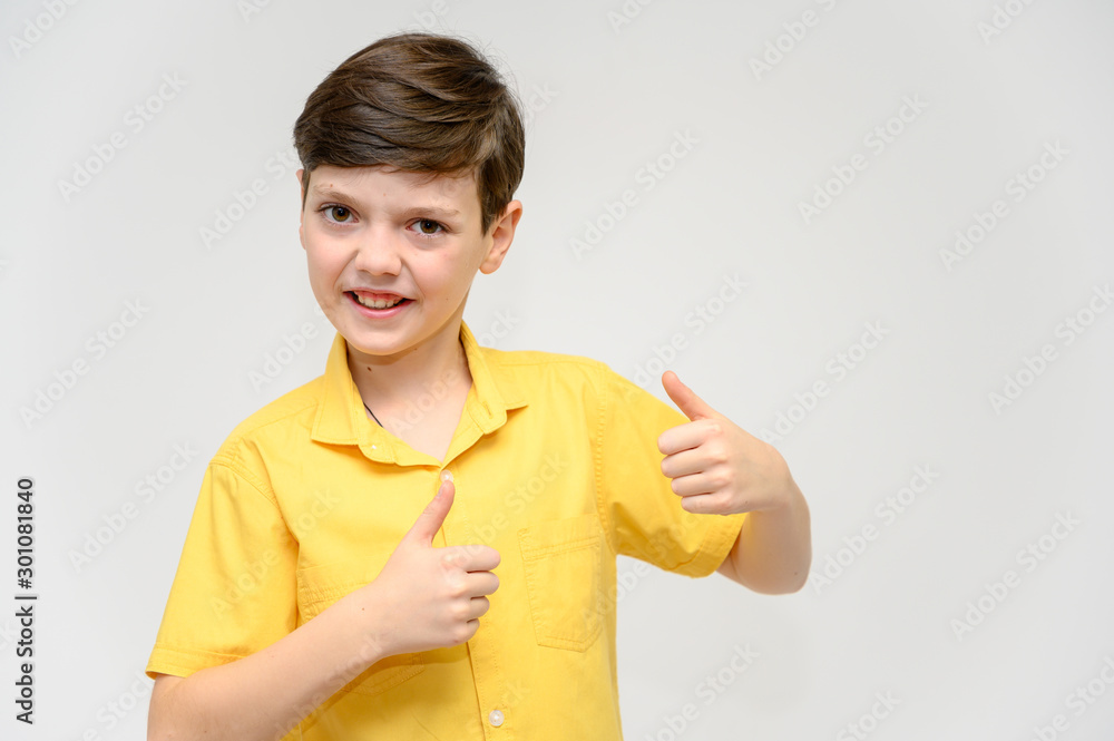 Concept boy teenager shows imitates the behavior of heroes from different movies. Portrait of a child on a white background in a yellow shirt. Standing in front of the camera in poses with emotions. Concept boy teenager shows imitates the behavior of heroes from different movies. Portrait of a child on a white background in a yellow shirt. Standing in front of the camera in poses with emotions.