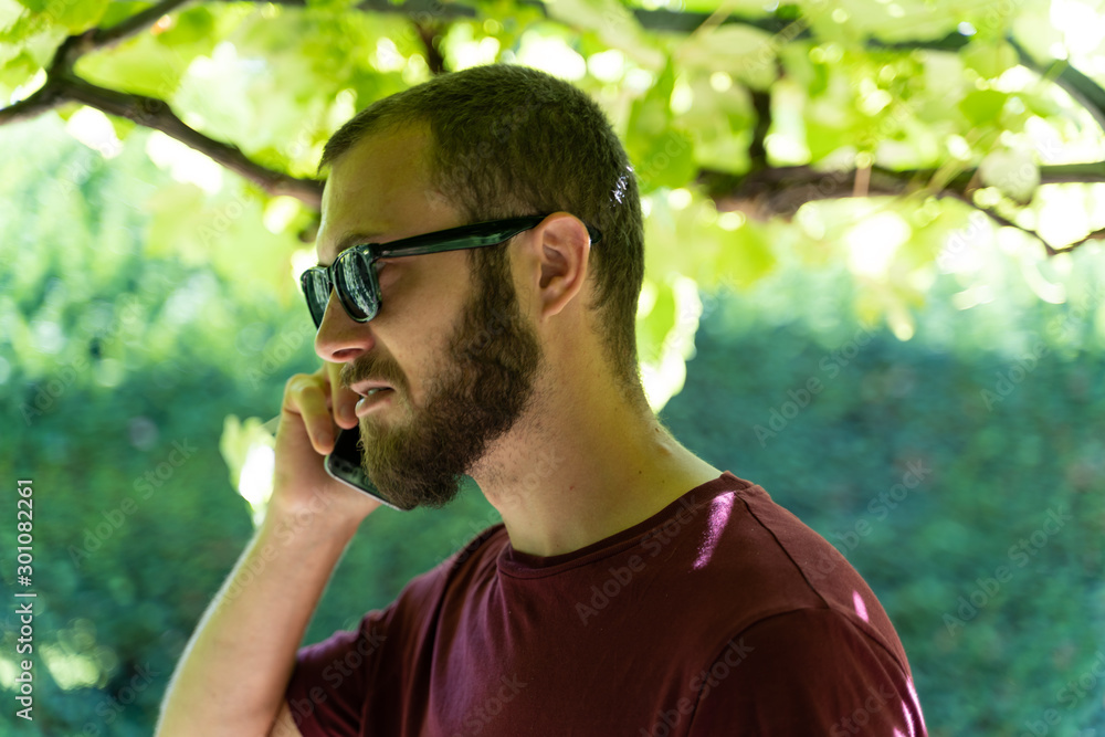 Boy with sunglasses under a grapevine talking on his mobile Boy with sunglasses under a grapevine talking on his mobile