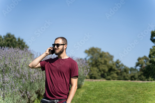Boy with sunglasses in the middle of a garden talking on a mobile phone