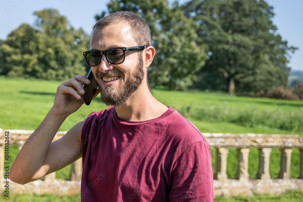 Man with sunglasses smiling and talking to the mobile phone