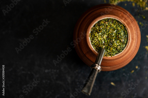 Beautiful composition of yerba mate on a black background - Juicy and green leaves without sticks photo