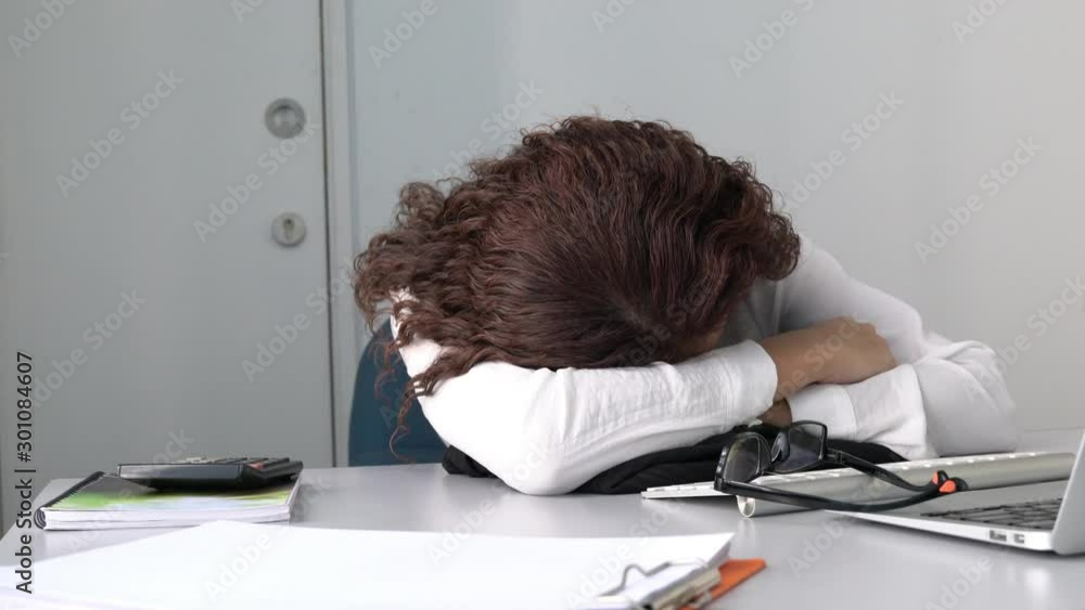 Tired employee or office executive sleeping on her office desk in front of her computer. Overwork or tired from work concept. Tired employee or office executive sleeping on her office desk in front of her computer. Overwork or tired from work concept.