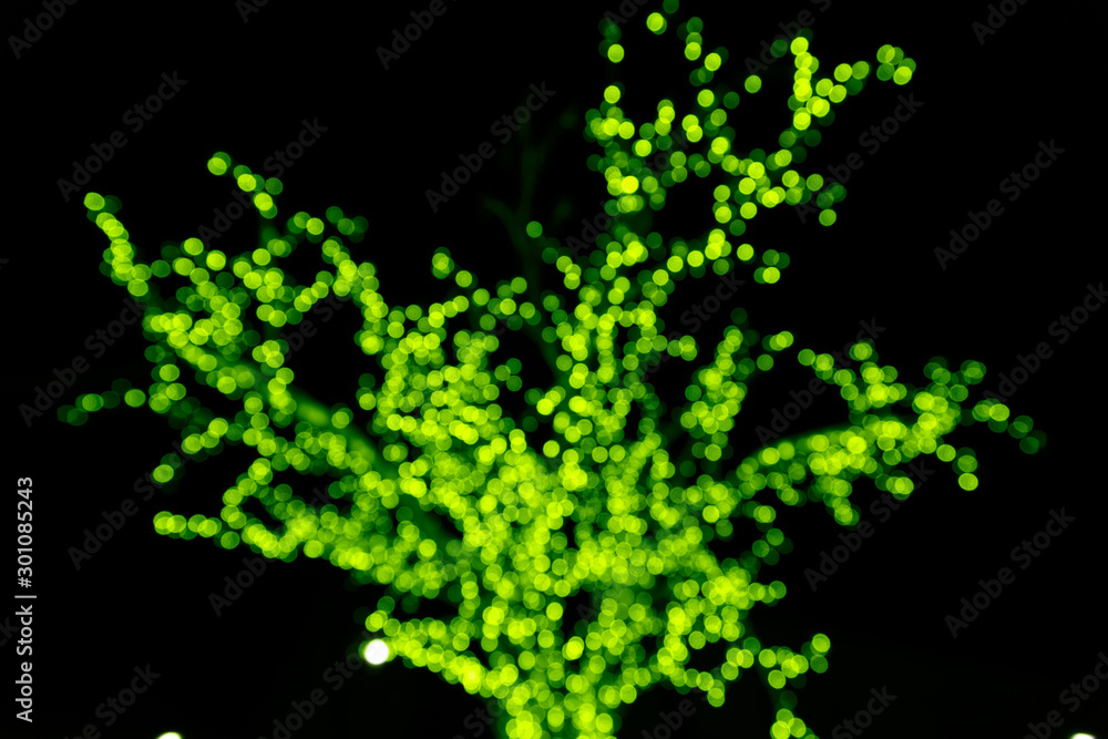 Green tree silhouette made of glowing blurry circles from New Year's bulbs on a black background. Green tree silhouette made of glowing blurry circles from New Year's bulbs on a black background.
