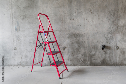 Red ladder against concrete wall of room interior under construction