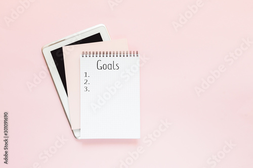 Top view of a flat lay of desktop and notepads for writing down goals and plans. 2020 New Year's goal, plan, action text on notepad with office accessories. Business motivation, inspiration concept.