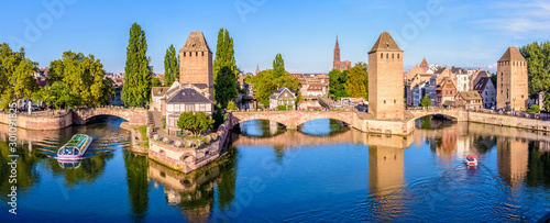 Panoramic view of the Ponts Couverts on the river Ill at the entrance of the Petite France historic quarter in Strasbourg, France, with a tour boat and an electric renting boat cruising on the canals.