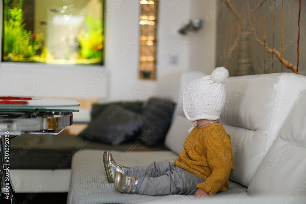 Obraz premium One baby in a knitted hat and sweater on the sofa