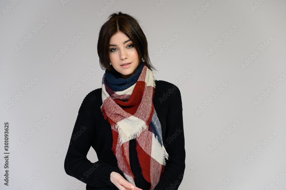 Close-up portrait of a young pretty girl student with long black hair with a scarf and in a sweater, on a white background. Standing right in front of the camera in different poses with emotions. Close-up portrait of a young pretty girl student with long black hair with a scarf and in a sweater, on a white background. Standing right in front of the camera in different poses with emotions.