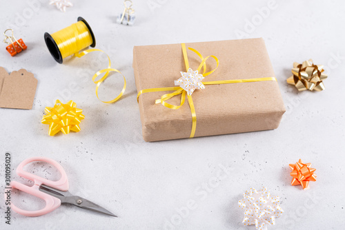 Flat lay with present, wrapping paper, ribbon, bow and scissors on white background