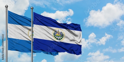 Nicaragua and El Salvador flag waving in the wind against white cloudy blue sky together. Diplomacy concept, international relations.