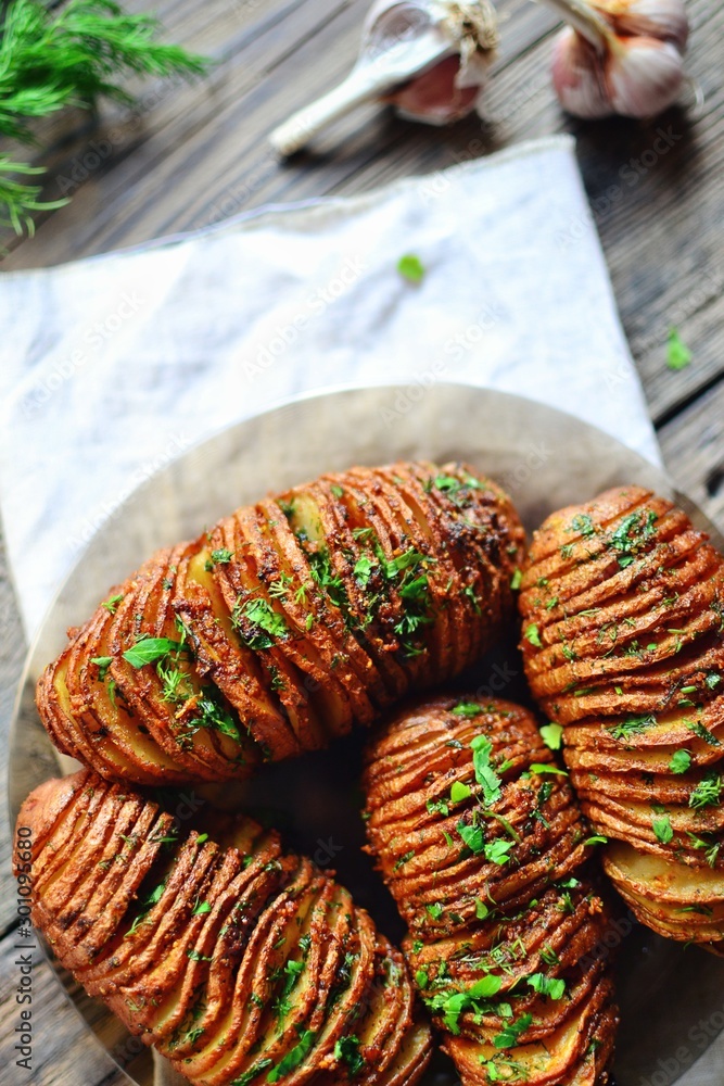 Hasselback potatoes.Horizontal view, Appetizing potato accordion baked in the oven. Potato on a wooden background.