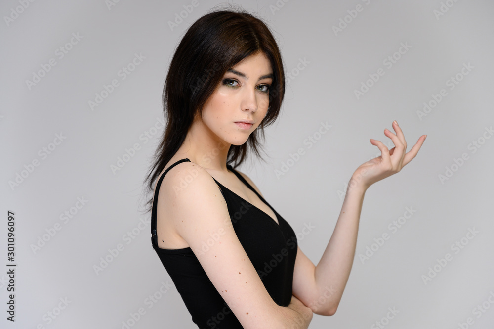 Close-up portrait of a young pretty girl student with long black hair, on a white background. He stands right in front of the camera, showing his hands in different poses with different emotions. Close-up portrait of a young pretty girl student with long black hair, on a white background. He stands right in front of the camera, showing his hands in different poses with different emotions.