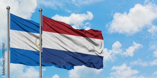 Nicaragua and Netherlands flag waving in the wind against white cloudy blue sky together. Diplomacy concept, international relations.