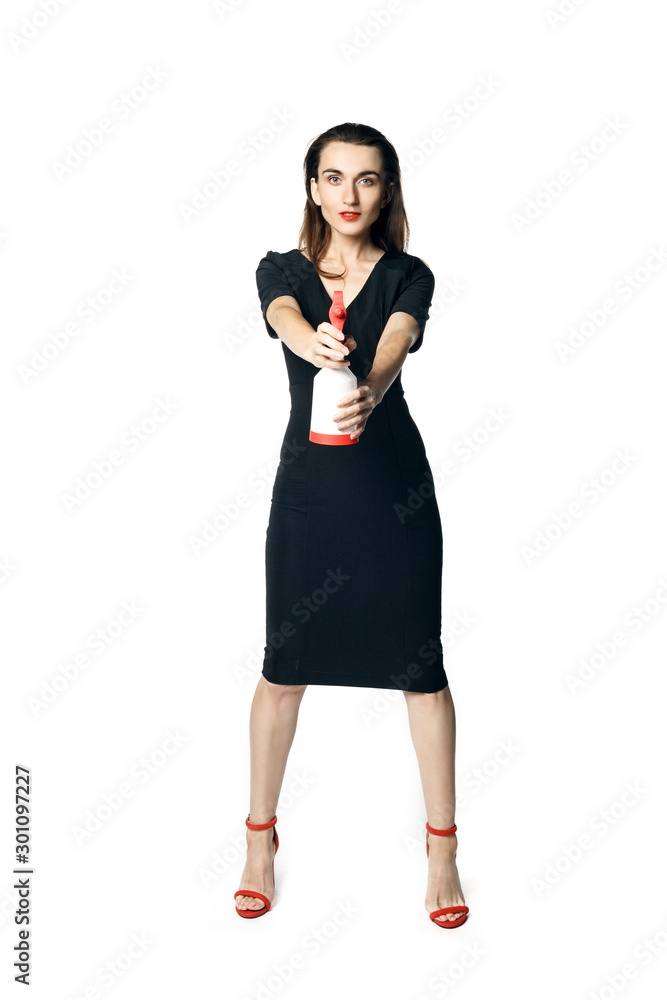 The fatal woman in a black dress with a spray for washing glasses pretending to be a secret agent, holding a spray like a gun. Isolated on a whit The fatal woman in a black dress with a spray for washing glasses pretending to be a secret agent, holding a spray like a gun. Isolated on a whit