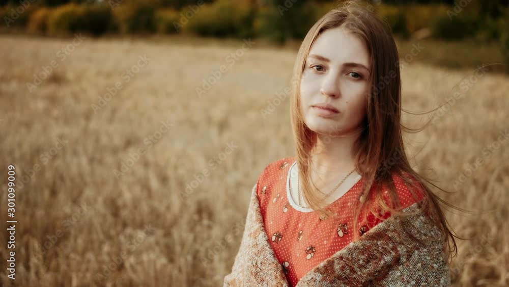 Portrait of beautiful young girl standing at a wheat field looking at camera in the Sunset light. Modern farming, happy youth and profession concept. Organic Products Concept. Agriculture industry. Portrait of beautiful young girl standing at a wheat field looking at camera in the Sunset light. Modern farming, happy youth and profession concept. Organic Products Concept. Agriculture industry.